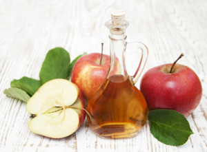 Apple cider vinegar and fresh apple on a wooden background
